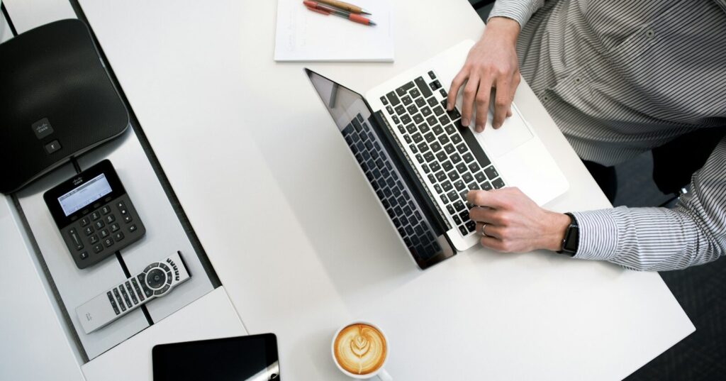 person using laptop on white wooden table